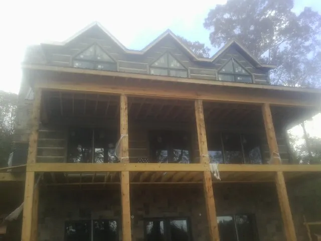 Dormers and porch framing on a large log home under construction — Roof Coating work by our crew in Fairhope