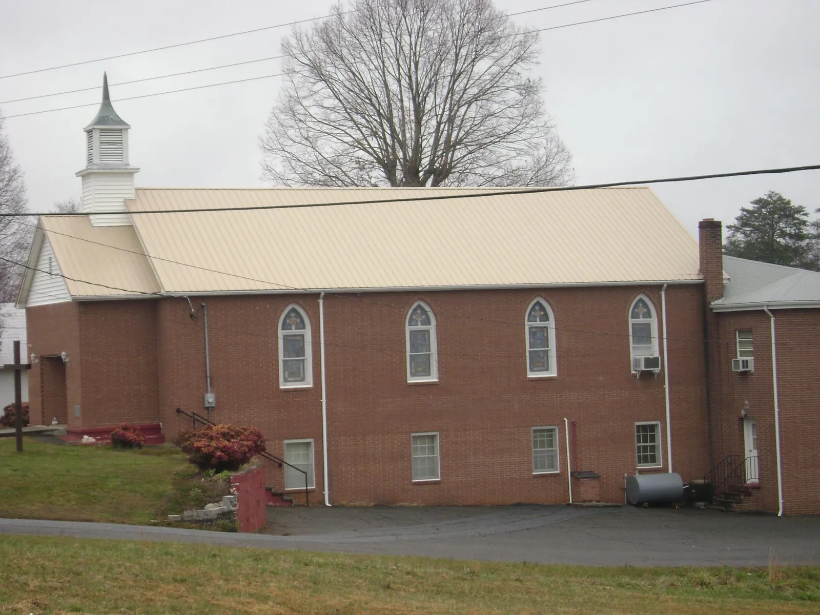New tan metal roof on a brick church with a white steeple in Fairhope