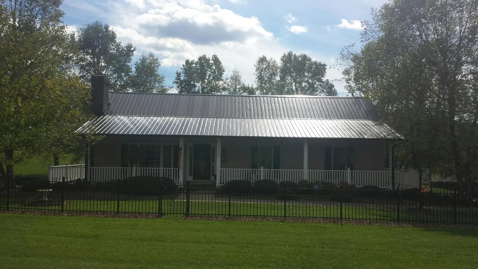 Gray metal roof on a brick ranch with a full width front porch — Gutter Guard Installation work by our crew in Fairhope