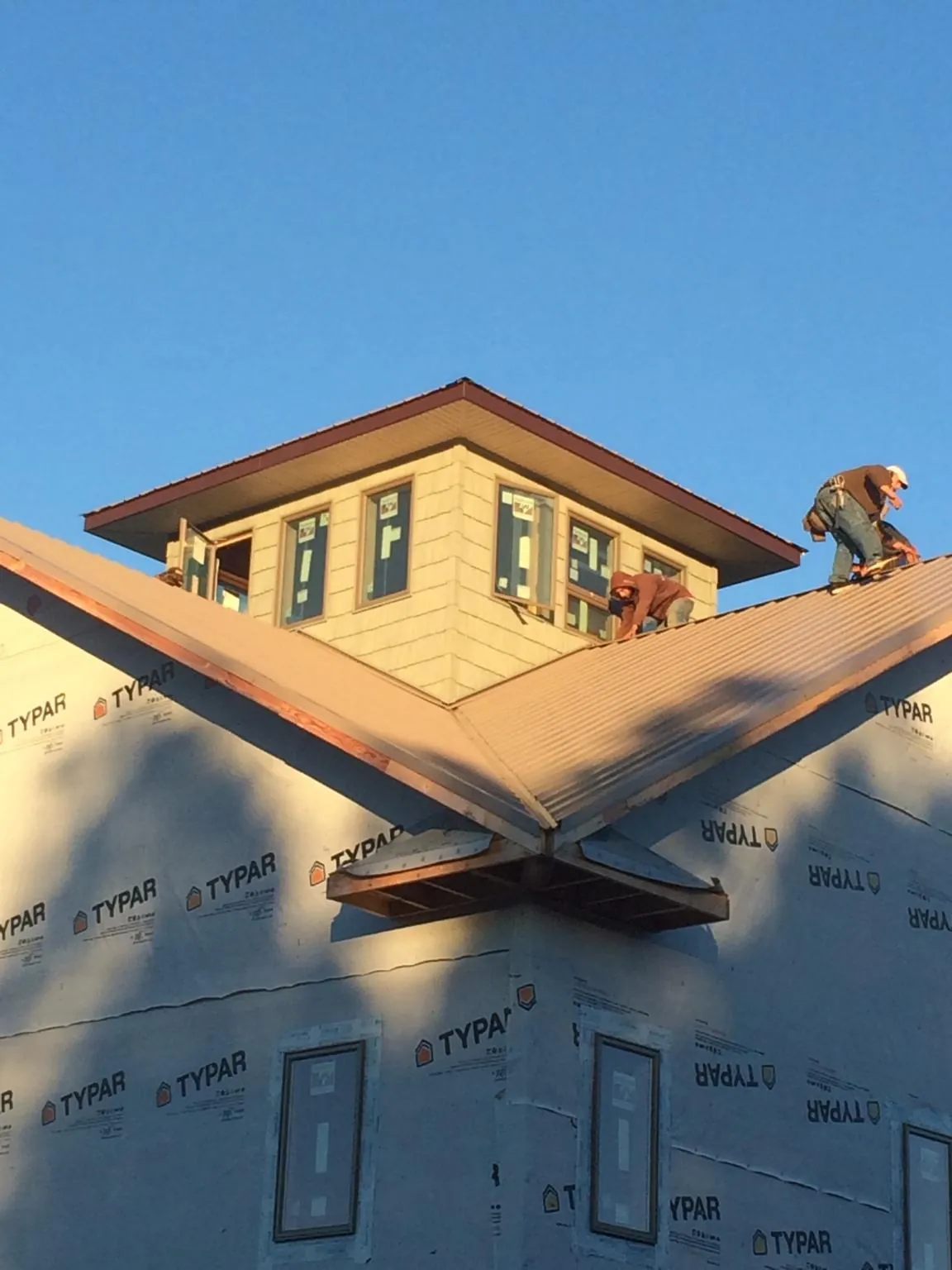 Roofers working around a rooftop cupola on a new metal roof at sunset — Roof Waterproofing in Fairhope by Roofing Brothers